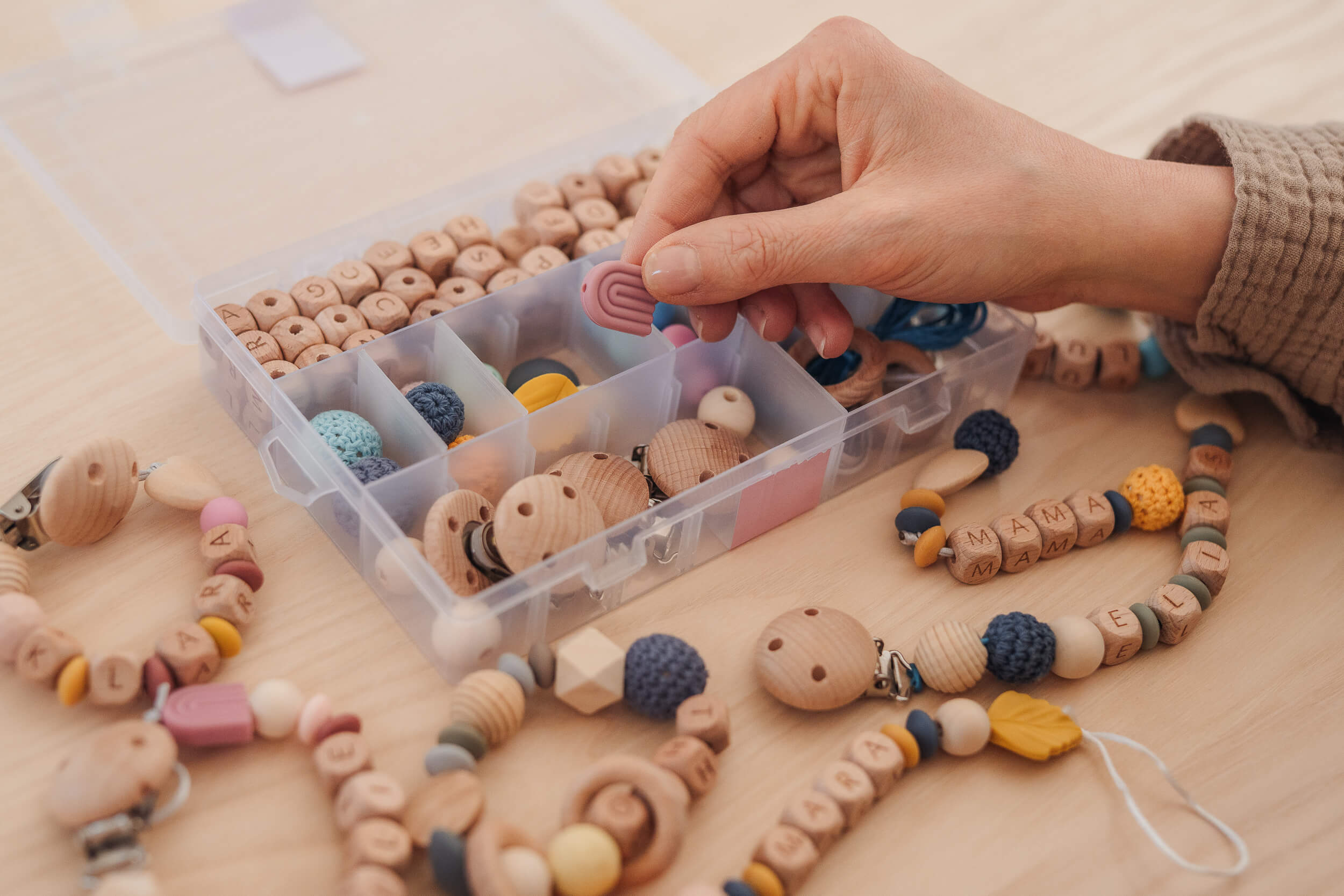 Hand mit Einzelteilen von Schnullerketten Bastelset