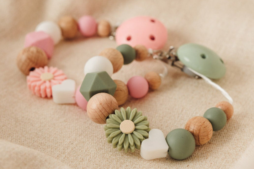 Schnullerketten liegen auf Stoff